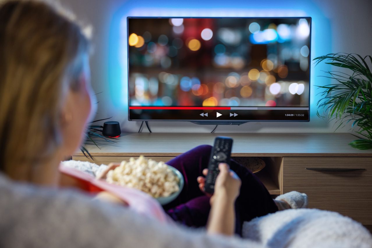 Woman relaxing at home in evening and watching TV