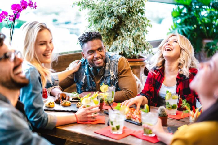 Young friends drinking mojito cocktails at fancy pub restaurant - Life style concept with multicultural people having fun together on happy hour at trendy bar - Vivid filter with focus on central guy