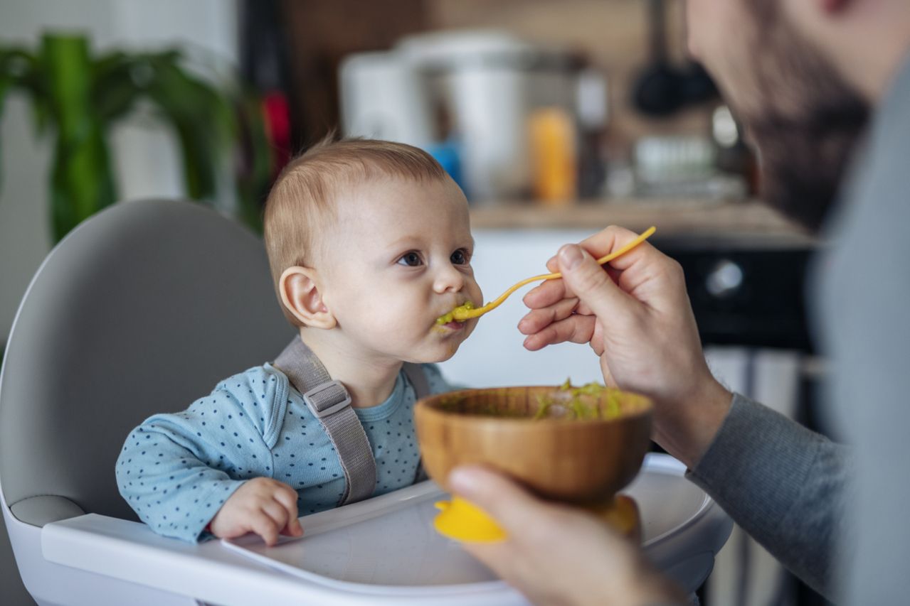 Caring single father spoon feeding his beautiful son.