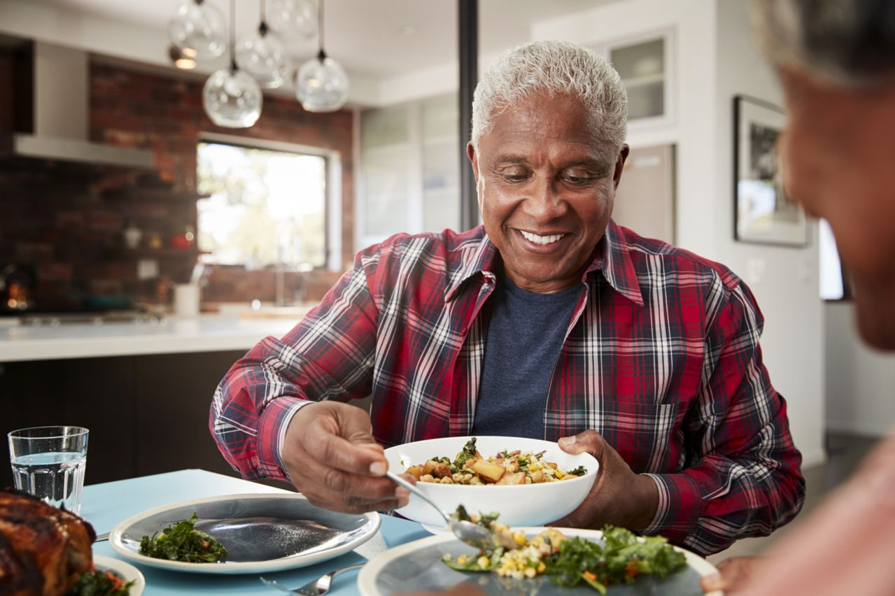 Senior Couple Enjoying Meal Around Table At Home